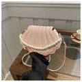Detailed view of pink shell bag with quilted texture and elegant pearl top handle - Pink