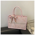 Detalle de bolso tote rosa con estampado floral y pañuelo sobre un sofá de cuero - Rosa
