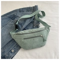 Close-up of light green corduroy fanny pack with dual zippers and triangle charms - Light Green