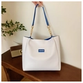 Detalle de bolso tote blanco con interior azul, cadena dorada y etiqueta Fashion de moda - Tipo estándar / Azul