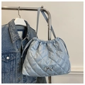 Detail of light blue quilted tote bag featuring drawstring and silver bow accent - Blue