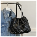 Detail of quilted black tote bag featuring a silver bow and drawstring closure - Black