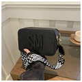 Dettaglio borsa squadrata in Saffiano nero con logo SM e tracolla larga geometrica - Nero