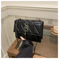 Nahaufnahme einer schwarzen Stepptasche mit silberner Metallschnalle auf einem Holztisch - Schwarz