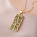 Detail of gold abacus pendant with green gemstones and pavé crystals on silk background - Emerald Green Abacus