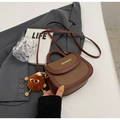 Brown leather saddle bag with plush ball charm and gold trim on grey blazer jacket - Brown (With Pendant)