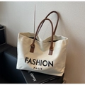 Close-up of canvas tote bag with brown leather handles and Fashion Paris print - Off White
