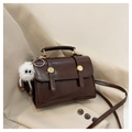 Detail of dark brown faux leather bag with gold buckles and white plush charm - Coffee with Pendant