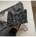 Detail of shimmering sequin texture and silver metal chain strap on a black clutch bag - Colorful