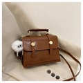 Detail of a brown leather crossbody bag with gold hardware and white plush charm - Brown with Pendant