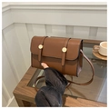 Detail of a brown rectangular messenger bag with gold hardware on a wooden table - Brown