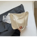 Chic cream patent leather bucket bag with a delicate bow accent on a neutral blazer - White