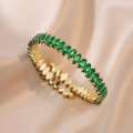 Detailed close-up of a gold bangle with marquise-cut green zircons on champagne silk - Emerald Green (TS163)