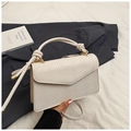 Close-up of cream woven handbag with knotted handle detail and metallic gold hardware - White
