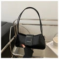 Dettaglio borsa a mezzaluna in vernice nera su ripiano in vetro con vari accessori - Nero