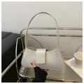 Detail shot of pearl white crescent bag with brand embossing in a modern cafe setting - Silver