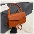 Detail of caramel woven texture handbag with twisted handle and gold hardware links - Brown