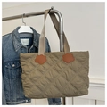 Close-up of quilted puffer tote bag with orange flower patches and diamond stitching - Green
