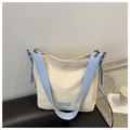 Dettaglio della borsa tote in tela con spalline in pelle azzurra su un cuscino nero - Bianco e Blu