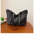 Détail d'un grand sac cabas noir matelassé en nylon posé sur une table en bois décorée - Noir