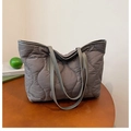 Détail d'un sac cabas matelassé gris plissé en nylon sur une table ronde en bois - Gris