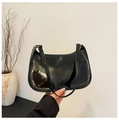 Close-up of black patent leather baguette bag featuring glossy finish and gold metal buckles - Black