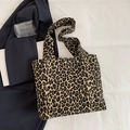 Leopard print canvas tote bag shown with blue blazer on a white fabric surface - Brown