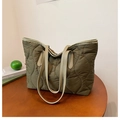 Gros plan du sac fourre-tout matelassé vert olive avec anses en cuir beige sur table - Vert