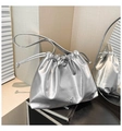Chic metallic silver drawstring bucket bag featuring a decorative metal bow accent - Silver