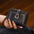 Close-up of black PU leather mini wallet with gold snap closure and beige stitching - Black