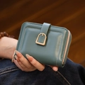 Close-up of minimalist teal and pink PU leather wallet with U-shaped buckle detail - Green