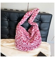 Close-up of pink leopard print plush tote bag with soft faux fur texture on black sofa - Rose Red