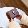 Close-up of vintage brown leather coin purse with flower buckle and leaf patterns - Coffee