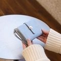 Détail du portefeuille bleu clair avec bouton floral doré et broderie de feuilles - Bleu Ciel