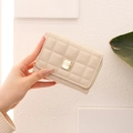 Close-up of beige quilted trifold wallet with gold metal logo and zipper details - Apricot