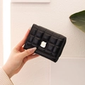 Close-up of black quilted small wallet with silver metal buckle and zipper detail - Black