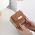Close-up of brown leather and suede short wallet with golden metal buckle clasp - Coffee