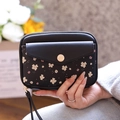 Detailed view of black floral passport wallet featuring a metal buckle and wrist strap - Black