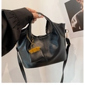Detail of black PU leather tote bag featuring a decorative yellow mini bag charm and strap - Black