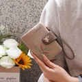 Close-up of a short PU leather wallet with colorful leaf prints and a bird-shaped clasp - Apricot