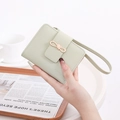 Close-up of light green lychee leather wallet with a bow buckle and hand strap - Green
