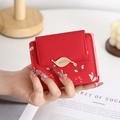 Detail of red small bifold purse with golden leaf clasp and cherry flower prints - Red