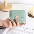 Macro detail of mint green PU leather wallet with floral print and gold leaf clasp - Green