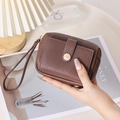 Gros plan sur la texture cuir litchi marron et le bouton pression doré de la pochette - Marron