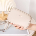 Detailed macro view of the cream-colored textured faux leather and dual zipper closure - Apricot