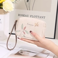 Detail of cream PU leather wallet featuring floral prints and golden bird logo with wristlet - Off White