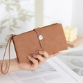 Detail of tan long wallet with stitched pattern, logo buckle, and wrist strap on a magazine - Yellow Brown