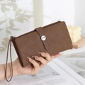 Brown long PU leather wallet with scalloped stitching and bow detail held by wristlet - Coffee