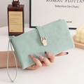 Primer plano de la cartera mate verde menta con hebilla metálica dorada y logo grabado - Verde
