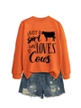 Close-up of bright orange sweatshirt with cow print paired with distressed denim shorts - Orange (Black Font)